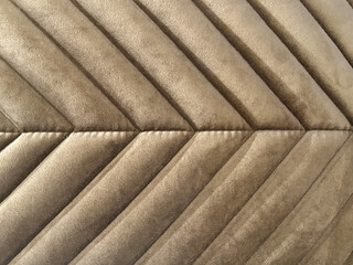 Close up of fabric in chevron pattern, in golden brown color. Chevron pattern upholstered panel in antique gold suede fabric. Seamless background texture.