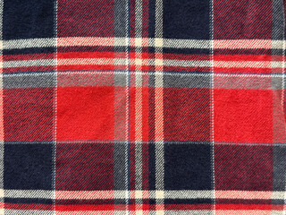 Close up of fabric with tartan pattern. In red, black, and white color. Flannel or tartan style is very common in scarf, shirts, and fashion industry. Seamless background texture.