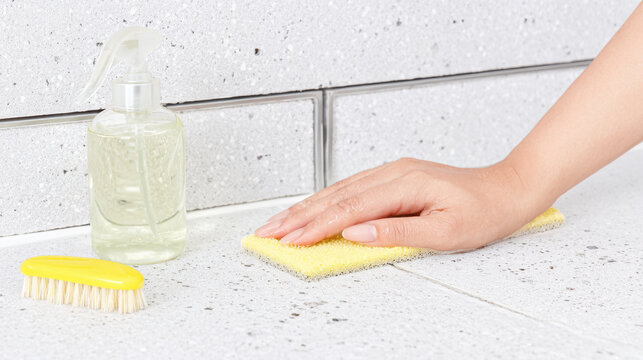 Hand scrubbing countertop with sponge and spray bottle