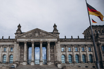 Historical architecture of the Reichstag building in Berlin with German flags.