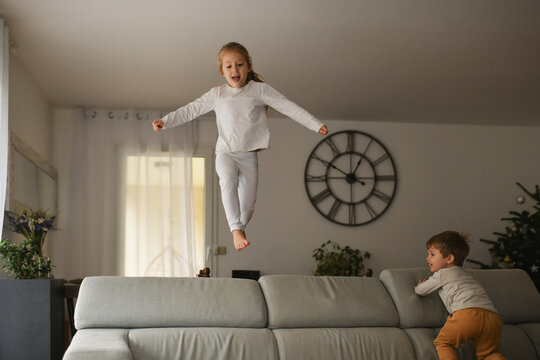 The children are jumping with joy on the sofa at Christmas