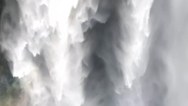 Dynamic close aerial view of Sk&oacute;gafoss waterfall showing intense white water, swirling mist and dramatic textures as the water crashes into the plunge pool. Atmospheric and powerful natural scene.