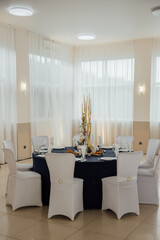 Elegant dining table setting with white chairs and floral centerpiece for formal event.