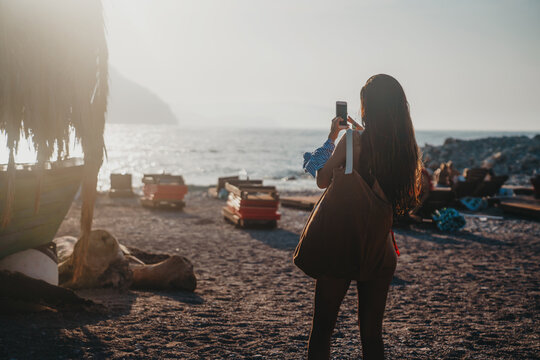 Fit girl hold on smart phone gadget in sandy coastline. She taking summer memories with smartphone