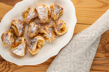 Fragrant mini strudel with apples on a white ceramic dish, top view. macro.