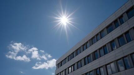 Modern building facade under a bright sunlit blue sky with visible sun rays and scattered clouds