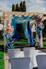 Elegant outdoor wedding ceremony set up with floral arch and white chairs