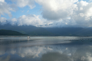 Tranquil Lap An Lagoon in Hue, reflecting cloudy mountains under a vast, atmospheric sky.