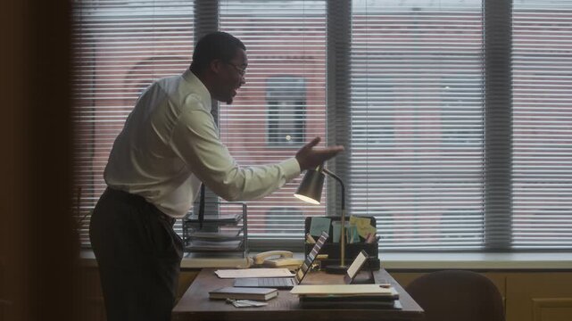 Medium long shot of African American male school principal greeting young woman with teenage daughter in office