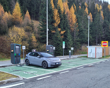 Bolzano, Italy - Nov 04, 2025: A static shot of a grey Volkswagen ID4 charging at the Brennero DC charging station in a sunny winter day. Selective focus