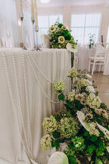 Elegant wedding table decor with floral arrangements and pearl details.
