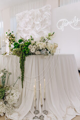 Elegant wedding decor with floral arrangements and candles on a white draped table.