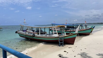 Obraz premium Two traditional wooden boats resting on a sandy beach next to clear turquoise ocean water under a bright blue sky with a distant pier.