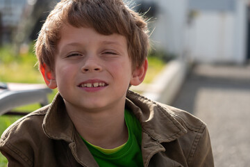 Boy with a green shirt and brown jacket is smiling