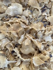 Close-up view of numerous dried, crispy, light-brown food flakes or chips.