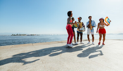 Group of friends playing music by the seaside