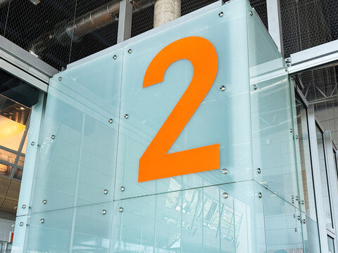Passengers wait at Warsaw Modlin Airport in Nowy Dwor Mazowiecki beside a large orange number two sign