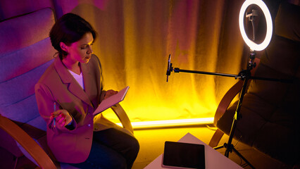 Woman coaching online with phone and ring light. Concept of digital communication, personal branding, confident teaching energy for online-education and coaching media.