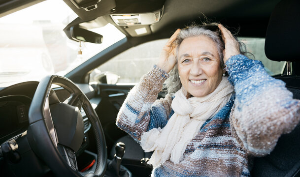 Senior woman smiling in car, enjoying driver lifestyle