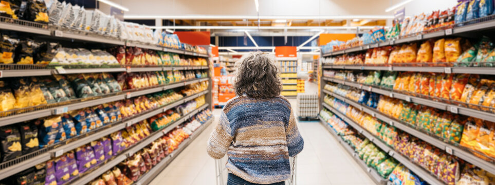 Woman making choices in supermarket snack aisle