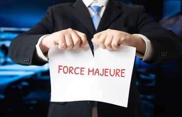 Businessman tearing a sheet of paper with the word Force majeure. Overcoming obstacles, resolving crises, and taking control of unexpected business challenges.