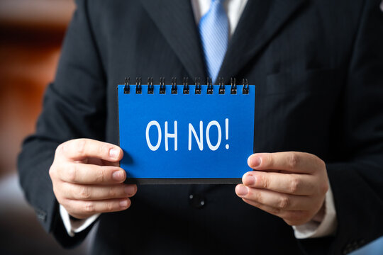 Businessman holding a notebook with the words Oh no. Expressing frustration, surprise, or reaction to a sudden work challenge. Concept of business stress or unexpected problems.