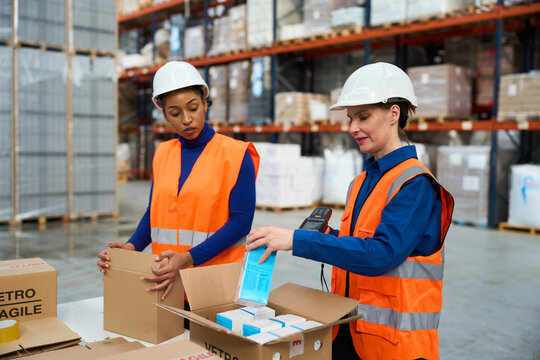 Women workers packing and scanning products in warehouse