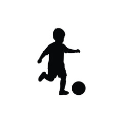 Young boy kicking a soccer ball in silhouette