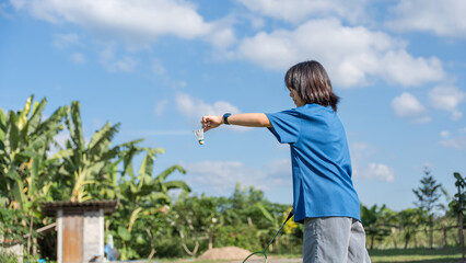 A girl holding a shuttlecock preparing to play badminton on a sunny day.