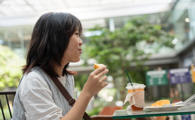 Happy teen girl eating snacks and chatting at an outdoor caf&eacute; in natural light.