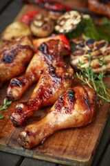 Grilled chicken drumsticks and vegetables on wooden board
