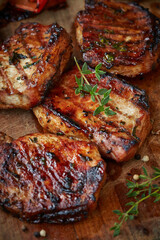 Grilling pork chops with thyme on wooden board
