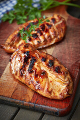 Grilled chicken breasts resting on wooden cutting board