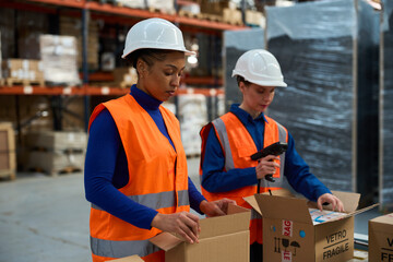 Female workers packing shipping boxes in warehouse