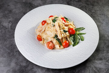 Creamy Pasta with Cherry Tomatoes, Spinach, and Basil on White Plate,Elegant Dinner Presentation