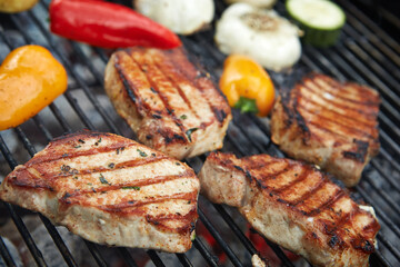 Grilling pork chops and colorful vegetables outdoors