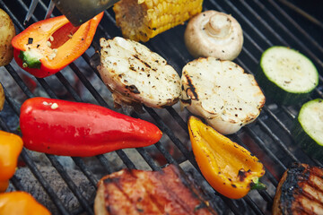Mixed vegetables and meat cooking on a hot grill outdoors