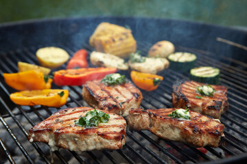 Grilling pork chops and vegetables on charcoal barbecue