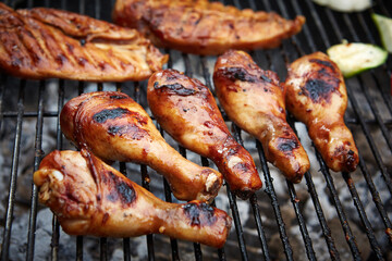 Chicken drumsticks and breast grilling on bbq grill
