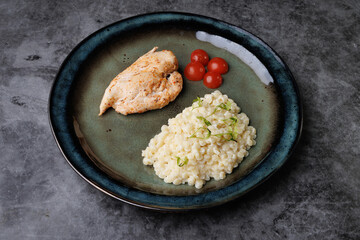 Gourmet Chicken With Creamy Risotto And Cherry Tomatoes On A Blue Plate