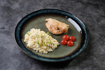 Gourmet Chicken With Creamy Risotto And Cherry Tomatoes On A Blue Plate