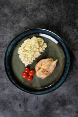 Gourmet Chicken With Creamy Risotto And Cherry Tomatoes On A Blue Plate