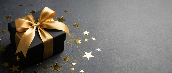 minimal black gift box with gold ribbon on charcoal background