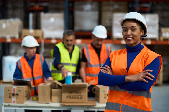 Female warehouse worker smiling with diverse team packing items