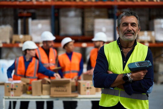 Warehouse manager holding scanner with logistics team