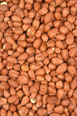 A vertical, overhead shot densely fills the frame with shelled and skin-on hazelnuts, showcasing their rich brown color and natural texture