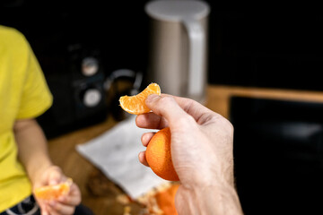 Parent offering a mandarin slice to a child in a cozy kitchen, capturing a warm family moment and healthy snacking