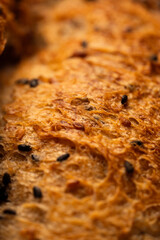 An extreme close-up macro shot capturing the intricate details of a freshly baked artisan bread crust. Black sesame seeds