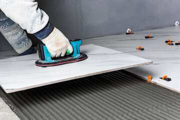 Laying the tiles using electric suction cup with automatic pumping.