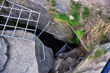 Jaskinia Malinowska - Stalowe bariery nad niebezpiecznym wejściem do podziemnej jaskini w skalistym terenie.